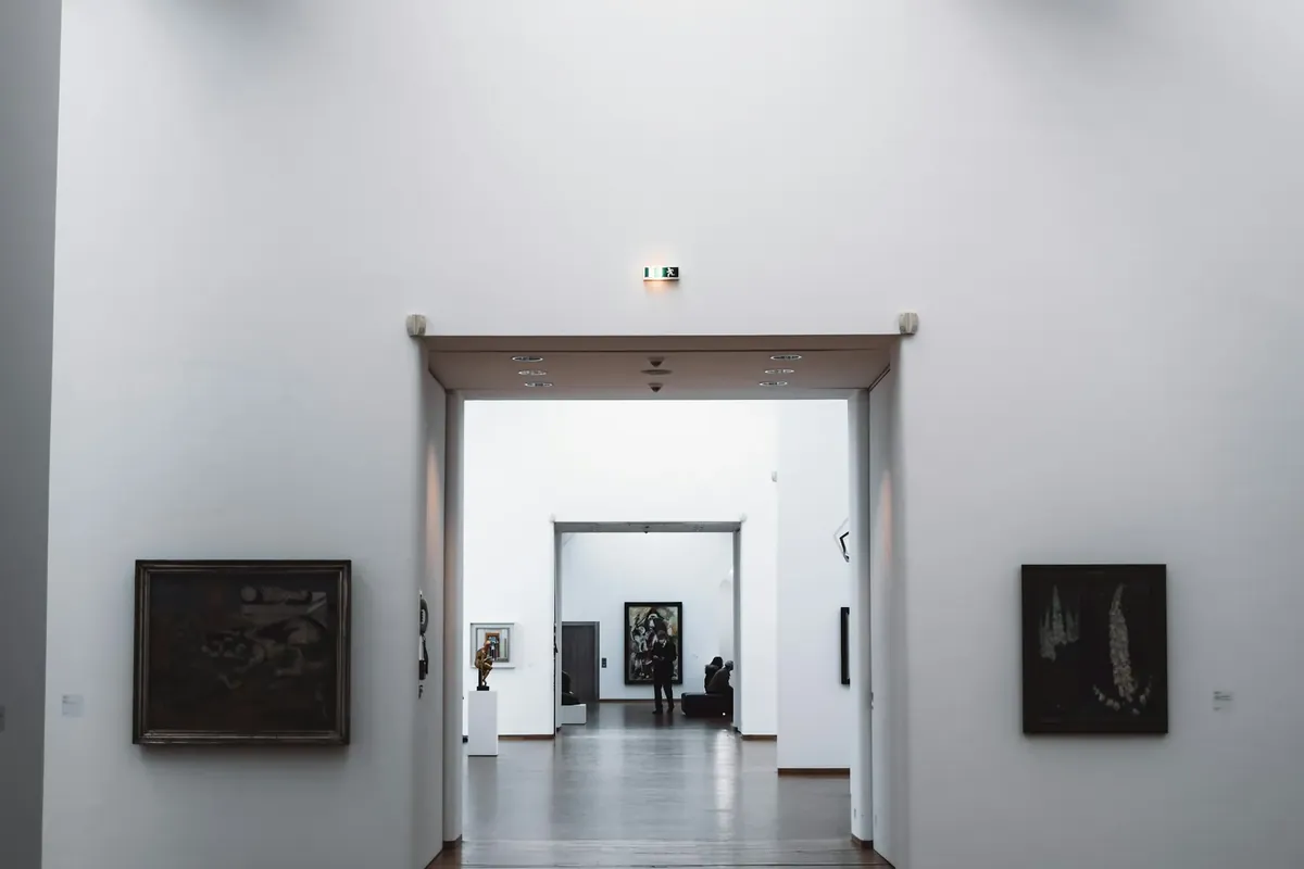A large white room hung with paintings